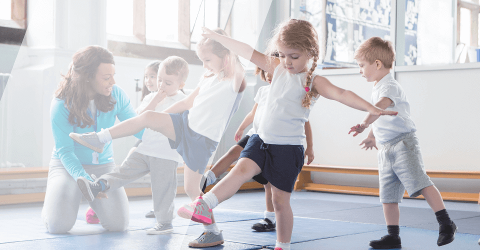 groupe d'enfant faisant de l'activité physique avec une animatrice dans une salle de sport