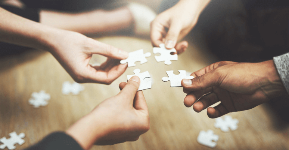 des mains qui se réunissent pour rapprocher des pièces de puzzle
