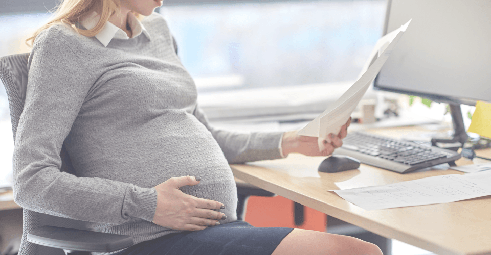 une femme enceinte au travail qui lit un rapport