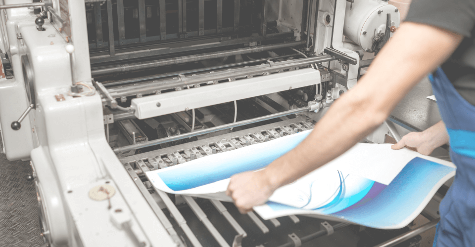 un ouvrier d'une imprimerie qui tient une feuille avec de l'encre bleue