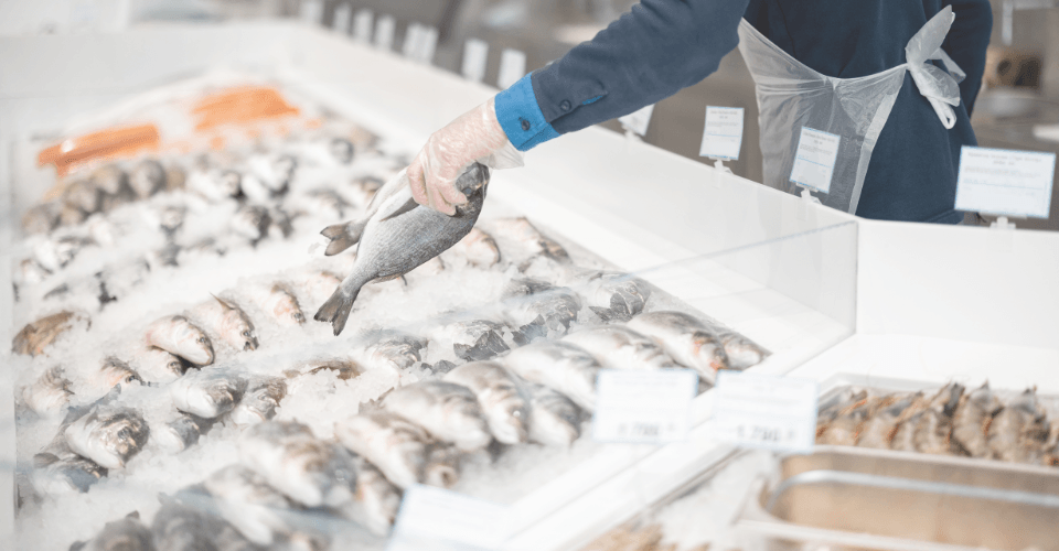 un poissonnier qui étale du poisson dans un supermarché