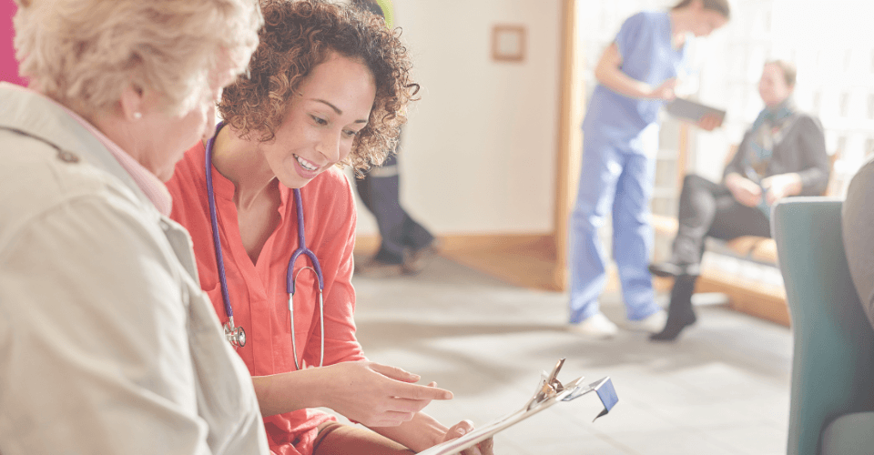 une patiente agée qui remplit un questionnaire dans une salle d'attente avec une médecin