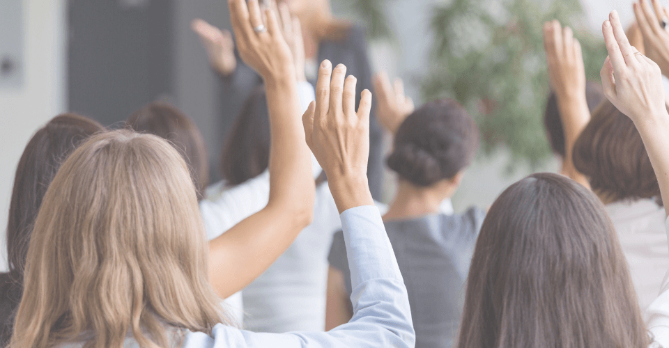 des personnes qui posent des questions en levant le main pendant une séance d'information