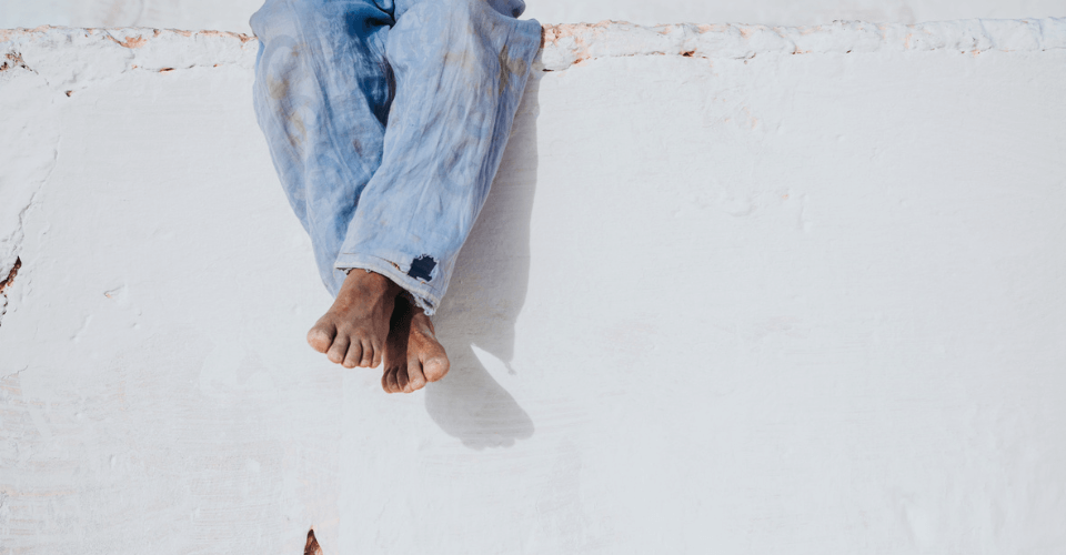jambe d'un enfant assis seul sur un mur décrépi
